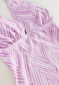 Tissu rayé rose et blanc avec un motif en zigzag ; texture douce avec des détails froncés aux épaules et à la couture de la taille.