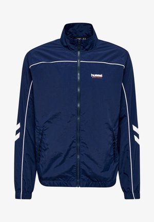 Marinefarbene Windbreaker-Jacke aus leichtem Material, mit Reißverschluss, hohem Kragen, weißen Akzenten und signatur Logo auf der Brust.