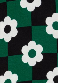 Mønstret stoff med grønne og svarte firkanter, prydet med hvite blomster som har svarte senter. Myk tekstur, livlige farger.