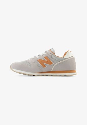 Baskets New Balance gris clair et orange, dessus en daim et mesh, lacets blancs, semelle rembourrée, logo sur le côté, présentées de biais sur fond blanc.