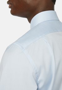 Ljusblå skjorta med klassisk krage, som har en mjuk textur och strukturerade axlar. Snygg sömnad längs sömmarna.