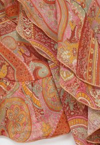 Zijden sjaal met ingewikkelde paisley- en bloemenpatronen in oranje, roze en goud. Zachte textuur met delicate stiksels langs de randen.