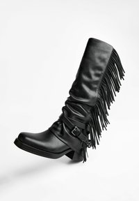 Black leather knee-high boot with fringe detailing, a buckle strap, and a square heel. Smooth texture and structured design.