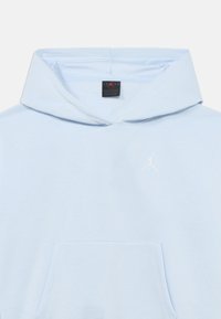 Φόρμα με κουκούλα σε ανοιχτό γαλάζιο χρώμα, κατασκευασμένη από απαλό βαμβάκι. Διαθέτει μπροστινή τσέπη και μικρό λευκό λογότυπο Jumpman στο στήθος. Ολοκληρώνεται με κουκούλα που κλείνει με κορδόνι.