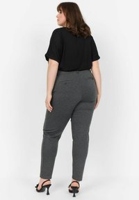 Haut noir à manches courtes associé à un pantalon gris foncé en matière extensible. Comprend des poches arrière et un design ajusté. Talons noirs avec des accents.