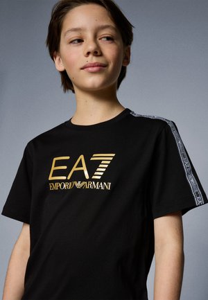 Black cotton t-shirt with bold gold "EA7 Emporio Armani" logo, featuring contrasting patterned stripes on the shoulders.