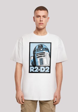 Hvit bomulls T-skjorte med trykt illustrasjon av R2-D2 i svart og blått, med "R2-D2"-tekst under i lyseblått mot en svart ramme.
