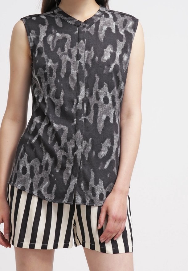 Sleeveless black top with gray leopard print, featuring a collar and button front. Paired with black and white striped shorts.