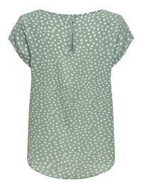 Blusa verde a maniche corte con motivo di puntini bianchi irregolari e chiusura con zip centrale sul retro.