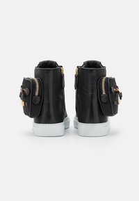 Svarta högskor med guldiga dragkedjor, vita sulor och små sidofickor. Slät läderliknande material med en elegant design.