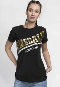 Black t-shirt with gold and white printed text "Lonsdale London." Short sleeves, crew neck, regular fit. Smooth fabric texture.