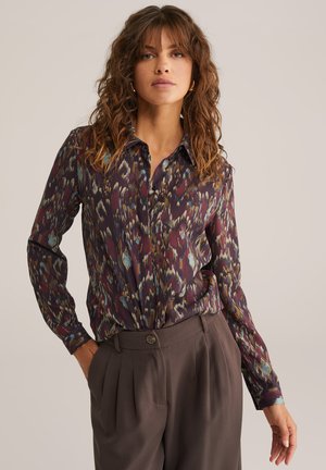 Camicia a maniche lunghe con colletto in un tessuto viola scuro, caratterizzata da un motivo astratto multicolore. Texture liscia, dettaglio con bottoni sul colletto.