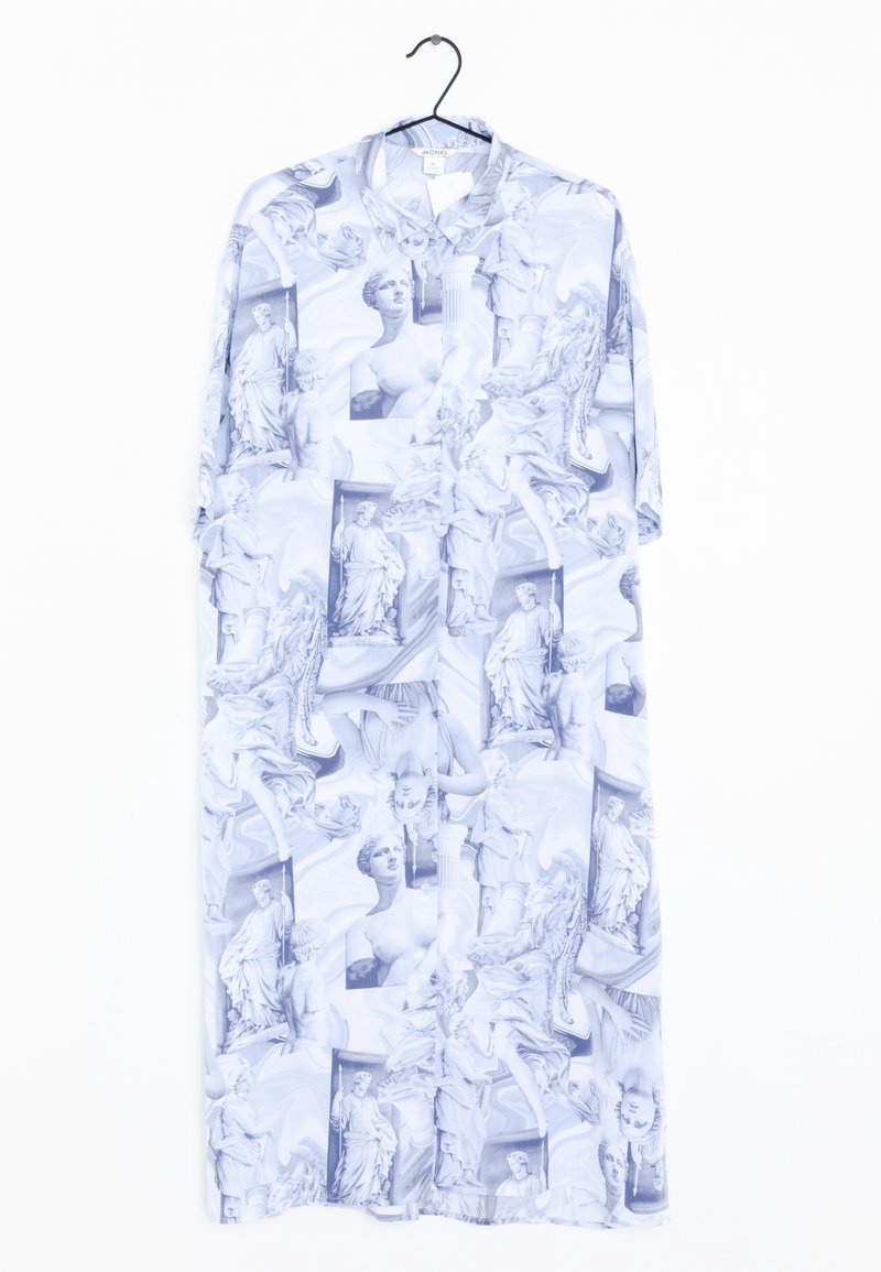 Longue robe chemise blanche avec des imprimés de statues classiques bleu-gris suspendue sur un cintre noir sur fond blanc.