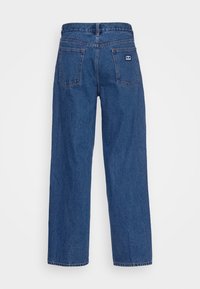 Modré džíny z denimu s rovnými nohavicemi, vybavené páskem, zadními kapsami a malou logovou nášivkou na pravé kapse.