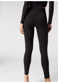 Leggings negros con una cintura alta y una textura suave y elástica. Diseño ajustado sin costuras ni patrones visibles, que ofrece una silueta elegante.