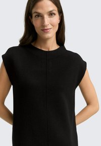 Zwarte mouwloze top met een ronde halslijn, gemaakt van textuurstof, met een verticale naad in het midden vooraan en minimalistische ontwerpelementen.