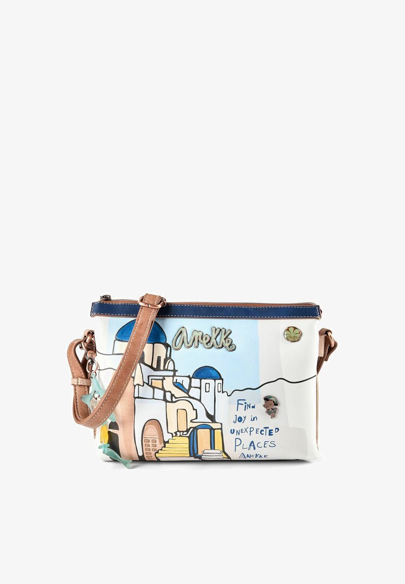 Petit sac bandoulière avec des bâtiments blancs de style Santorin et des dômes bleus, bandoulière marron, et texte « Trouvez la joie dans des endroits inattendus. »