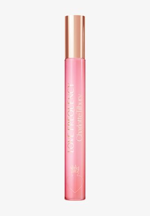 Schlanke pinke Parfümflasche mit roségoldenem Verschluss, beschriftet mit "Love Frequency Charlotte Tilbury" und herzförmigem Flammenlogo nahe dem Boden.