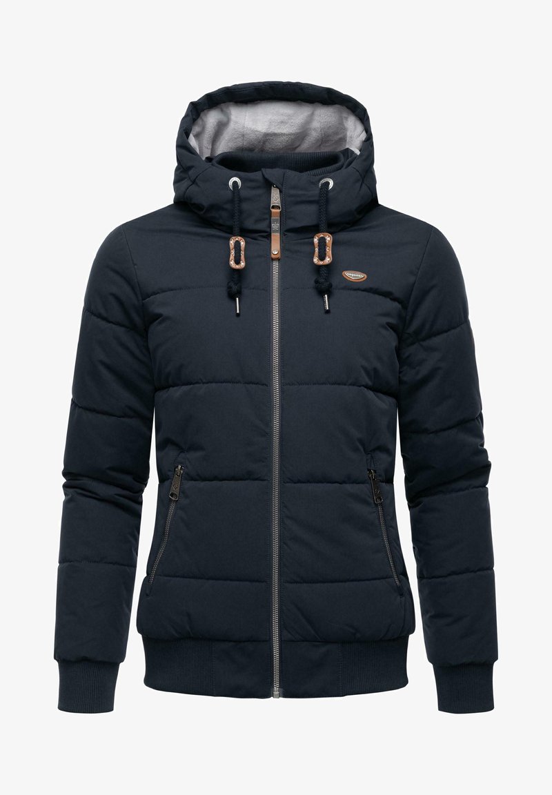 Tamsiai mėlynas pūkinis bleizeris su kapišonu, užtrauktuku, dviem šoninėmis kišenėmis, elastingomis rankovėmis ir dirbtinės odos akcentais. Tekstūruota, šilumą izoliuojanti medžiaga.