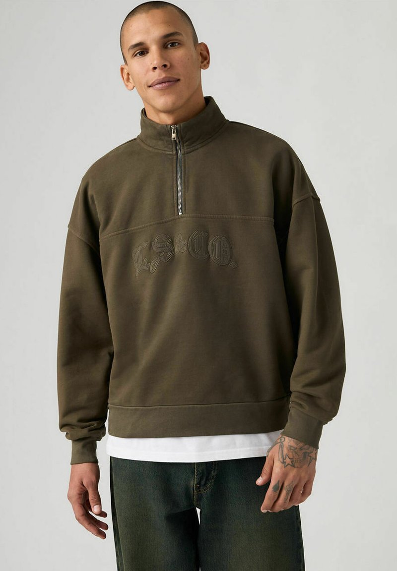 Sweat-shirt à col montant mi-fermeture éclair en tissu doux de couleur vert olive, doté de poignets côtelés et d'un logo embossé sur la poitrine.
