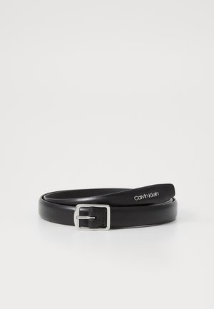 Sort læderbælte med sølv rektangulært spænde og "Calvin Klein" logo på spidsen, rullet på en hvid overflade.