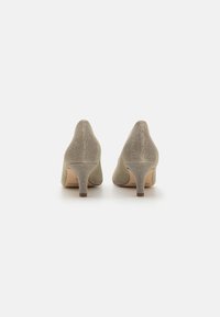 Beige high-heeled shoes with textured fabric, pointed toe, and a slender heel. The back features a smooth finish and subtle stitching details.