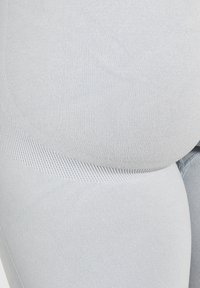 Leggings grigi chiari con una texture a costine e design senza cuciture. Caratteristiche includono una vestibilità flessibile e un sottile dettaglio a righe tono su tono lungo i lati.