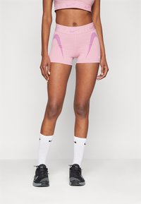 Rosa treningsshorts med kontrasterende lilla bølge-striper, tettsittende design, kombinert med svarte sko og hvite sokker med logoer.