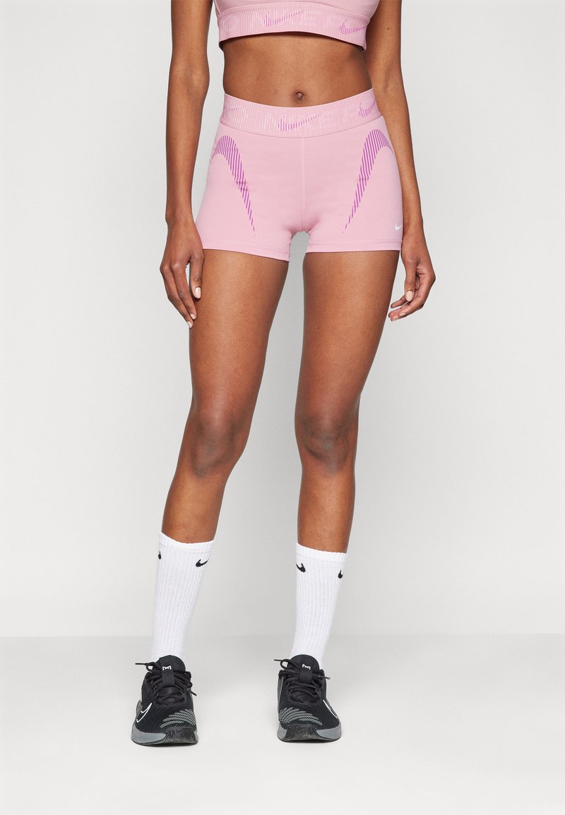 Rosa treningsshorts med kontrasterende lilla bølge-striper, tettsittende design, kombinert med svarte sko og hvite sokker med logoer.
