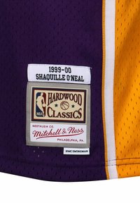 Lila Basketball-Trikot mit weißen und gelben Akzenten, perforierter Textur und einem Etikett mit "1999-00 SHAQUILLE O’NEAL" sowie Markendetails.