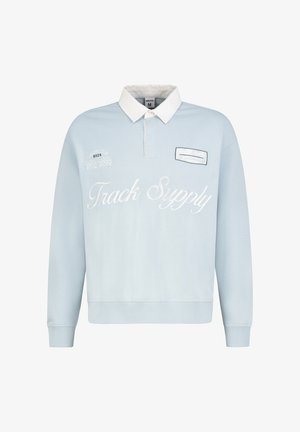 Hellblaues Polohemd mit langen Ärmeln und weißem Kragen, mit dem Schriftzug „Track Supply“ und kleinen gestickten Patches auf der Brust.