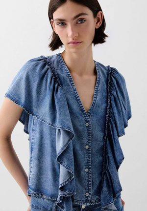 Blusa in denim con maniche corte a volant, scollatura a v e chiusura con bottoni. Colore blu chiaro a medio, con dettagli di cucitura a contrasto.
