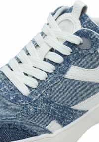 Sneakers in denim con lacci bianchi, caratterizzati da una combinazione di denim blu testurizzato e dettagli in pelle bianca, punta arrotondata e suola in gomma.
