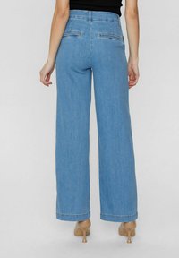 Jeans large bleu clair avec une taille haute, deux poches arrière et un ourlet épuré. Fabriqués en denim avec une texture lisse.