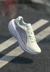 Αθλητικό παπούτσι ανοιχτού πράσινου με επάνω μέρος από διαπνέον δίχτυ, ροζ λεπτομέρειες, λευκή σόλα και μπλε λογότυπο Swoosh. Διαθέτει κορδόνια και υφή στην επιφάνεια.