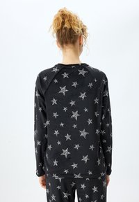 Zwarte zachte sweatshirt met een patroon van witte sterren en accenten in luipaardprint; lange mouwen en een relaxed fit.