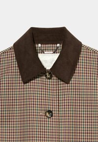 Colletto in velluto a coste marrone su una giacca a quadri con quadrati crema, bordeaux e verdi. Include un bottone nero e un'etichetta all'interno.