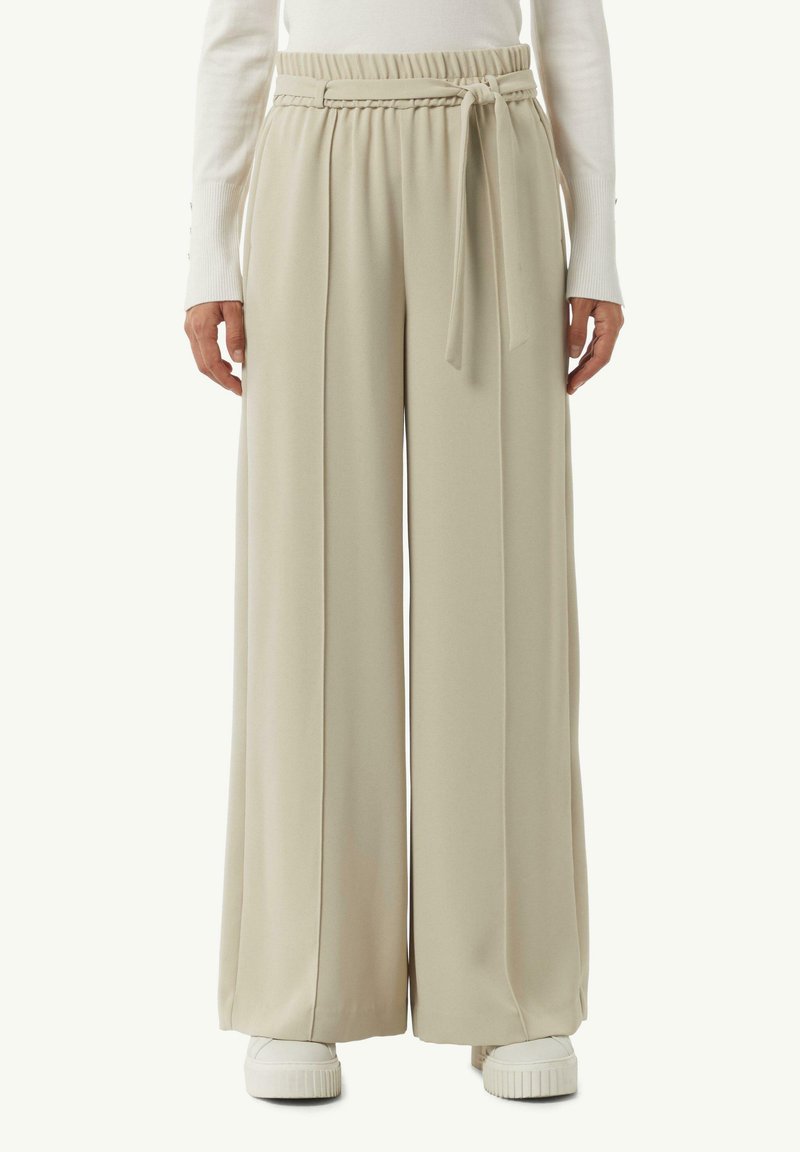 Beige wijde broek met een hoge elastische tailleband en een gevlochten riemdetail. Soepele, vloeiende stof met plooien aan de voorkant en een ontspannen pasvorm.