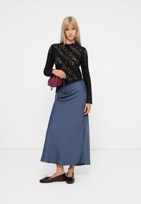 Schwarzes Spitzenoberteil mit langen Ärmeln, blaue Satin-Maxikleid, burgunderfarbene Umhängetasche und glänzende schwarze Loafers. Minimalistisches Design mit glatten Texturen.