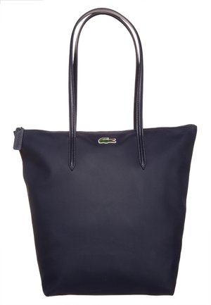 Bolsa tote azul marino con asas dobles largas, cremallera superior y pequeño logo de cocodrilo verde centrado cerca de la parte superior.