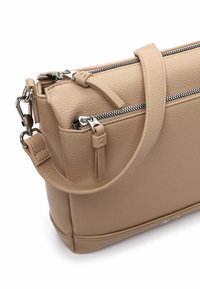 Beżowa skórzana torebka z teksturowanym wykończeniem, dwoma przegródkami na zamek, odpinanym paskiem oraz srebrnymi dodatkami.