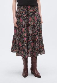 Czarna spódnica w wzory z żywymi motywami kwiatowymi i paisley. Luźny, warstwowy dół. Połączona z brązowymi, skórzanymi botkami na obcasie.