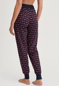 Marineblauwe pyjamabroek met een patroon van roze harten en strikken. Heeft een aansluitende tailleband en enkelsluitingen. Zachte, lichte stof.