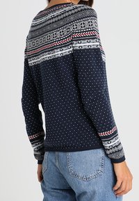 Marineblauer Pullover mit Punktenmuster und kompliziertem geometrischem Strickdesign an der Passe. Lange Ärmel mit gemusterten Bündchen. Baumwollmischgewebe.