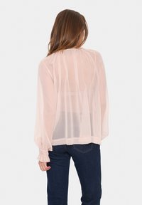Blusa rosa trasparente con maniche lunghe e puff, polsini elasticizzati e orlo dritto, caratterizzata da righe verticali per un tocco di texture in più.