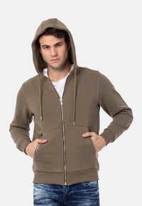 Bruine zip-up hoodie met een trekkoordcapuchon, voorzakken en geribbelde manchetten. Gemaakt van zachte stof met een gladde textuur.