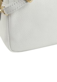 White textured leather handbag corner with gold-tone hardware and stitching detail. The surface features a slightly pebbled finish.