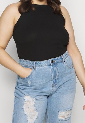 Sort ribbet tanktop parret med lyseblå højtaljede slidte jeans med revner og knaplukning.