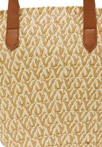 Woven straw tote bag with cream and natural straw patterns. It features two brown leather straps for carrying. The textured surface adds visual interest.