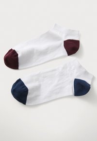 Chaussettes blanches à hauteur de cheville avec des embouts colorés ; l'une présente un embout bordeaux, l'autre un embout marine. Tissu doux et poignets côtelés.